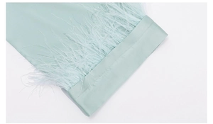 Detailed close-up of mint green satin pajama cuff featuring luxury feather trim decoration