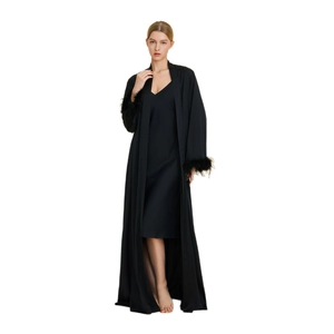 Women's black satin pajama set featuring a long robe with feather-trimmed sleeves and a slip dress