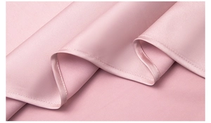 Detailed macro shot of premium pink satin fabric with smooth texture and fine stitching