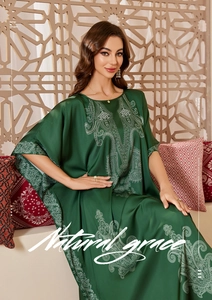 Detail of luxurious dark green satin caftan robe with white paisley and floral patterns