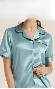 Detail view of mint green satin pajama top with black piping and white buttons