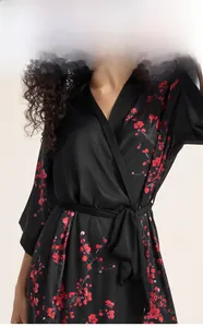 Detail of black satin robe featuring red plum blossom print and a kimono style neckline
