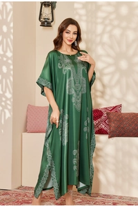 Detail of emerald green satin kaftan dress featuring white ethnic patterns and side slits