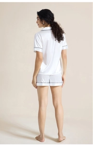 Back view of model wearing white satin pajamas set with contrast piping and shorts