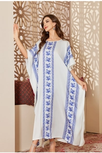 Detail of loose kaftan dress with blue floral prints on white satin fabric