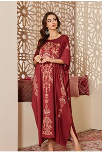 Detail of luxury gold Baroque patterns on a burgundy oversized satin kaftan robe