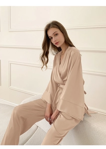 Détail d'un élégant pyjama en satin beige avec haut croisé à col en V et pantalon assorti