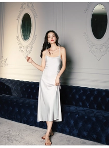 Détail d'une robe nuisette en satin blanc perle montrant la texture soyeuse et bretelles