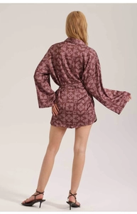 Back view of a woman in dark red geometric heart print satin pajama set with tie-waist