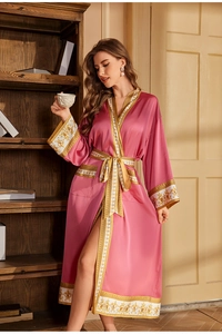 Détails d'un peignoir en satin rose luxueux avec bordures baroques sur les poignets