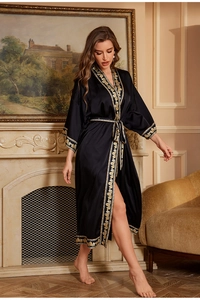 Detailed close-up of elegant black satin robe with luxurious gold baroque print trim