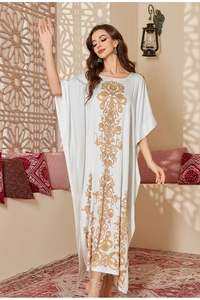 Detail of elegant white satin kaftan featuring intricate gold baroque floral patterns
