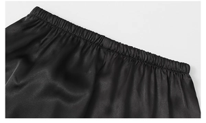 Detail of high-gloss black satin pajama shorts featuring a comfortable elastic waistband