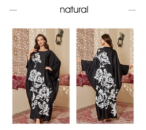 Detail of black satin long kaftan robe featuring oversized white rose prints and batwing sleeves
