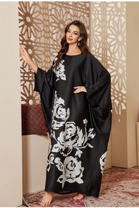 Detail of a black satin kaftan with white rose print and wide batwing sleeves