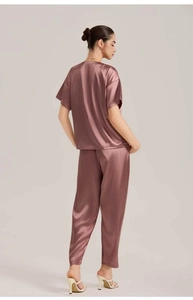 Rear view of pink satin short sleeve top and long trousers pajama set on a model