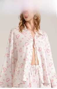 Detail view of white satin pajama set featuring pink heart patterns and waist tie closure