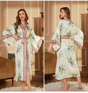 Détail d'un peignoir en satin vert clair à fleurs avec bordures géométriques et ceinture