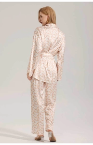 Close-up of orange and white satin pajamas with geometric print and waist tie belt