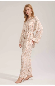 Close-up of lightweight satin pajama set with orange abstract print and drape detail