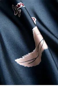Close-up of dark satin fabric texture featuring pink banana prints and red calligraphy