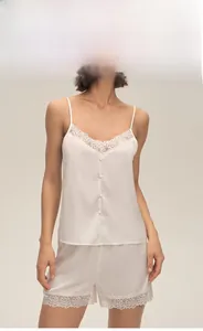 Detailed view of white silk pajamas featuring delicate lace trim and elegant fabric buttons