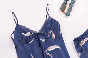Detail of navy blue silk pajama top with delicate lace edges and feather print