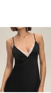 Détail du col en V avec bordure en dentelle blanche sur une nuisette en satin noir