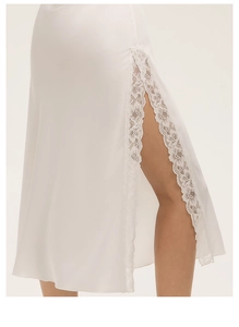 Dettaglio della gonna in raso bianco con elegante spacco laterale e bordo in pizzo