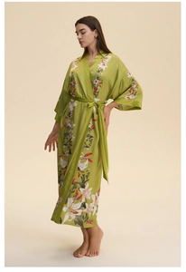 Detail showing the white lily floral pattern on a green satin long-sleeved bathrobe