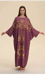 Detail of loose purple kaftan robe featuring golden baroque floral pattern on the front