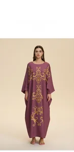 Close-up of golden baroque print on loose purple kaftan robe with elegant drape