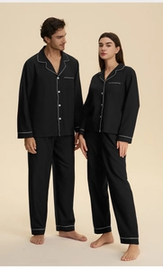 Detail of couple pajamas showing white piping on black cotton long-sleeved loungewear set