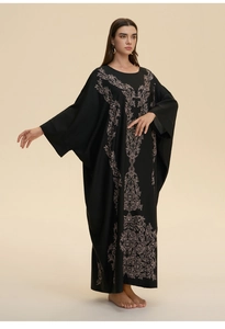Detailed view of luxury gold baroque print on a loose black kaftan with batwing sleeves