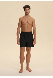 Close-up of black cotton lounge shorts with elastic waistband on male model