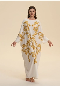 Detail of white kaftan dress with golden baroque patterns and wide kimono sleeves
