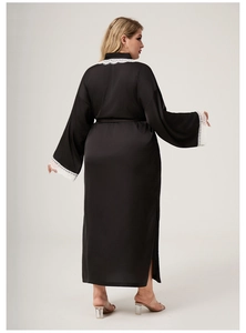 Rear view of long black satin bathrobe with white lace details on sleeves and hem