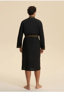 Detail of men's black robe featuring retro gold patterned trim on the back and cuffs