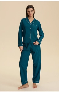 Detail of dark teal women's long-sleeve pajama set with white piping and silky texture