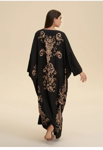 Detailed view of black caftan back featuring golden baroque scroll pattern print