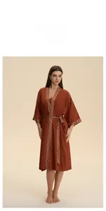 Détail du peignoir en satin rouge brique avec motifs ethniques sur le col et les poignets