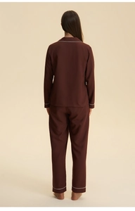Detail view of brown loungewear pajamas set with white piping on collar and sleeves