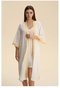 Détail d'un peignoir en satin blanc avec bordure florale jaune et nuisette en soie