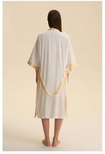 Détail d'un peignoir en satin blanc avec broderie géométrique jaune et bords bohèmes
