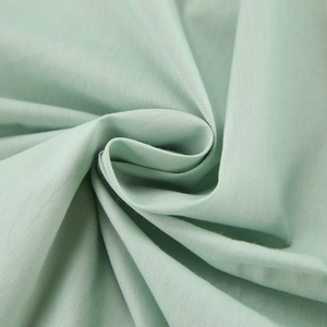 Detail view of breathable mint green cotton fabric with soft texture and natural drape