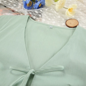 Detail of mint green V-neck cotton pajama top with tie-front knot and size M label