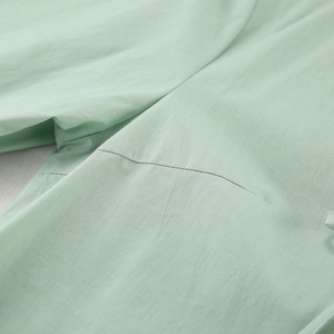 Close-up detail of light green cotton pajamas showing high-quality stitching and fabric texture