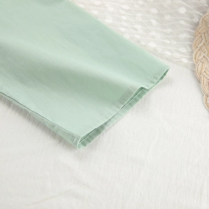 Detailed macro view of light green cotton sleeve cuffs with neat double-needle stitching