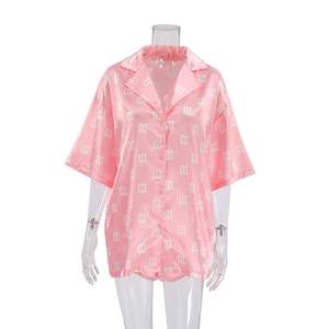 Detail of pink satin pajama top with white letter M prints and button-up lapel design