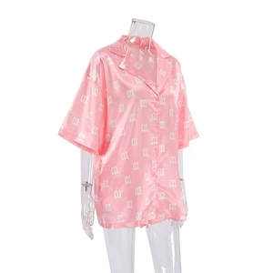 Detail of pink satin pajamas top showing M-letter print and notched collar texture